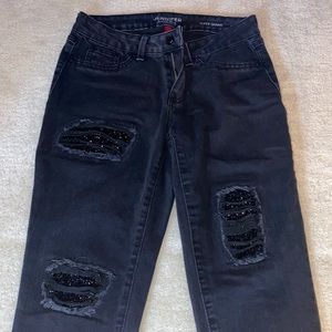 Jennifer Lopez super skinny black jeans with bedazzled patches on legs.